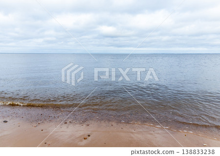 Soft sandy shoreline meets a calm sea with gentle ripples 138833238