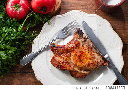 pork chop, on a light plate with fresh tomatoes and herbs, on a wooden table, daylight, no people, pork chop, on a light plate with fresh tomatoes and herbs, on a wooden table, daylight, no people, 138833255