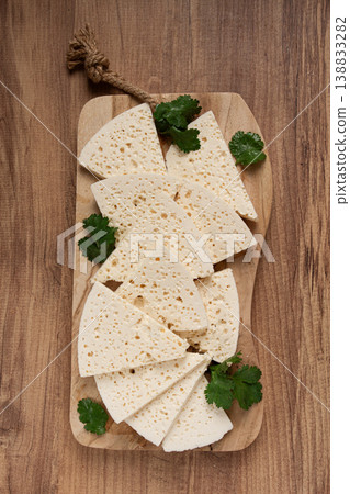 sliced Georgian cheese, factory grade, on a wooden board, top view, sliced Georgian cheese, factory grade, on a wooden board, top view, 138833282