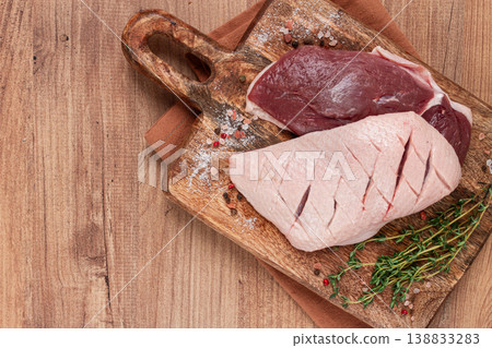 Fresh raw duck breasts, on a wooden chopping board, with herbs and spices, no people Fresh raw duck breasts, on a wooden chopping board, with herbs and spices, no people 138833283