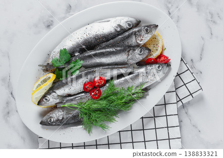 Fresh Herring fish, ready to cook, with herbs and spices, on a white platter, in the kitchen Fresh Herring fish, ready to cook, with herbs and spices, on a white platter, in the kitchen 138833321