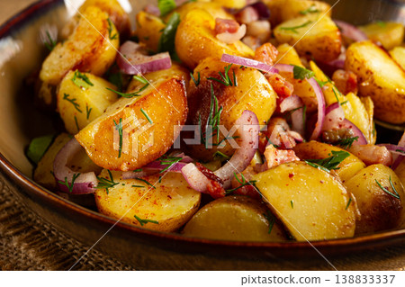 German potato salad with bacon, onions and herbs, plate on a wooden table, rustic style, no people, German potato salad with bacon, onions and herbs, plate on a wooden table, rustic style, no people, 138833337