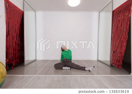 Young dancer performing a unique stretch in a minimalist indoor space with vibrant red decor and soft lighting Young dancer performing a unique stretch in a minimalist indoor space with vibrant red decor and soft lighting 138833619