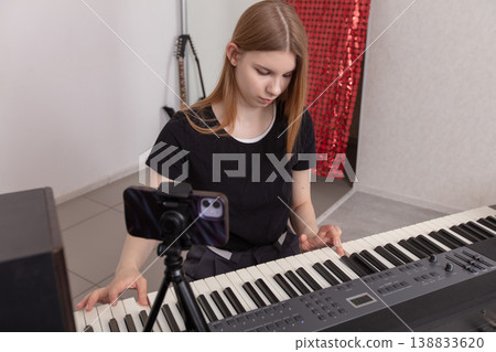 Young musician plays keyboard and practices music in a home studio setting during a focused afternoon session Young musician plays keyboard and practices music in a home studio setting during a focused afternoon session 138833620