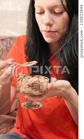 Woman enjoys dessert with chocolate ice cream in a cozy indoor setting Woman enjoys dessert with chocolate ice cream in a cozy indoor setting 138833694