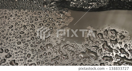 Water droplets gather on a metal surface creating various shapes and patterns during the afternoon 138833727