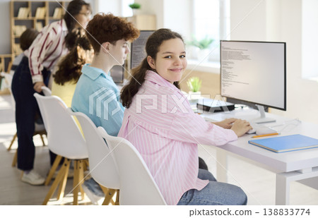 Smiling teenage students coding with teacher support in computer classroom 138833774