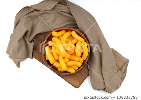 Cheese flavored corn puffs in wooden bowl isolated on white background, crunchy savory snack food Cheese flavored corn puffs in wooden bowl isolated on white background, crunchy savory snack food 138833788
