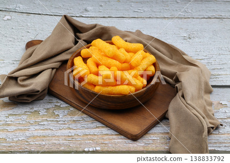 Cheese flavored corn puffs in wooden bowl on rustic wood background, crunchy savory cheese snacks 138833792