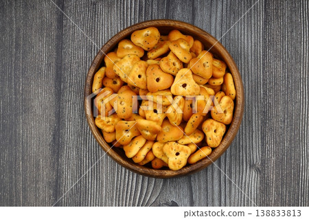 Spicy triangle crackers in a wooden bowl on rustic wood background, crunchy savory snack food 138833813