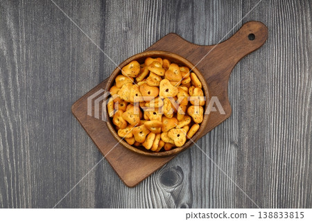 Spicy triangle crackers in a wooden bowl on rustic wood background, crunchy savory snack food 138833815