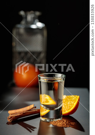 Mexican gold tequila with an orange slice and cinnamon on a black table. 138833926