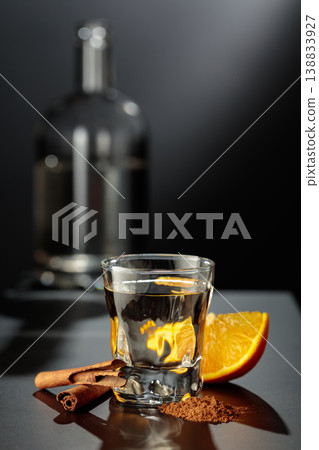 Mexican gold tequila with an orange slice and cinnamon on a black table. 138833927