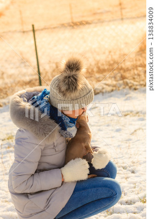 Woman playing with dog during winter Woman playing with dog during winter 138834009