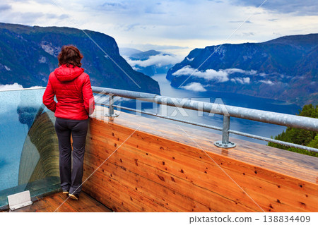Tourist enjoying fjord view on Stegastein viewpoint Norway Tourist enjoying fjord view on Stegastein viewpoint Norway 138834409