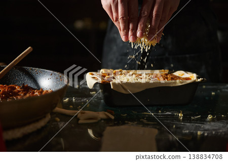 Sprinkling grated cheese over homemade pie before baking Sprinkling grated cheese over homemade pie before baking 138834708
