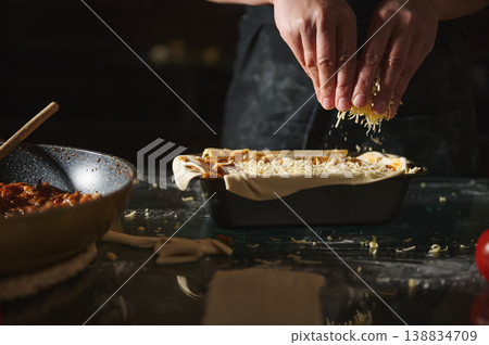 Adding cheese topping to homemade pie in baking tray Adding cheese topping to homemade pie in baking tray 138834709