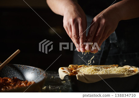 Close-up of sprinkling grated cheese on pie before baking Close-up of sprinkling grated cheese on pie before baking 138834710