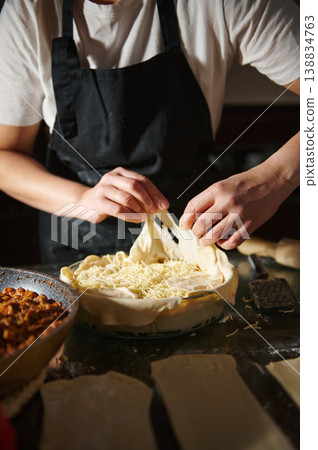 Woman placing dough layer over homemade pie with cheese filling Woman placing dough layer over homemade pie with cheese filling 138834763