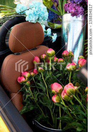 Smiling woman sits in yellow convertible surrounded by colorful flowers Smiling woman sits in yellow convertible surrounded by colorful flowers 138834817