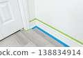 Interior corner of a room with painter's tape applied to walls and baseboards, preparing for painting and renovation work in a residential setting 138834914