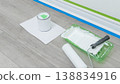 Paint supplies including a can, roller, and tray positioned on a wooden floor with painter's tape along the wall for home construction project 138834916