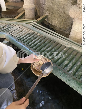 A woman washing money at Zeniarai Benzaiten Shrine 138835664
