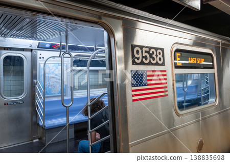 New york, usa august 15,2024. New york city subway e train interior with american flag sticker, passenger by doorway at last stop sign, urban commuter scene New york, usa august 15,2024. New york city subway e train interior with american flag sticker, passenger by doorway at last stop sign, urban commuter scene 138835698