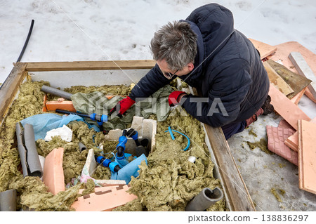 Plumber installing well pit distribution piping in winter in snowy rural area. Plumber installing well pit distribution piping in winter in snowy rural area. 138836297