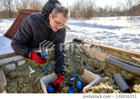 Connection of HDPE pipes with plastic compression fittings during installation of distribution piping in artesian well pit. 138836331