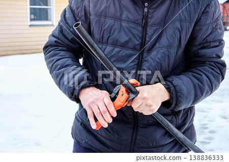 Ratchet pipe cutter in hands of plumber working with HDPE pipes. Ratchet pipe cutter in hands of plumber working with HDPE pipes. 138836333