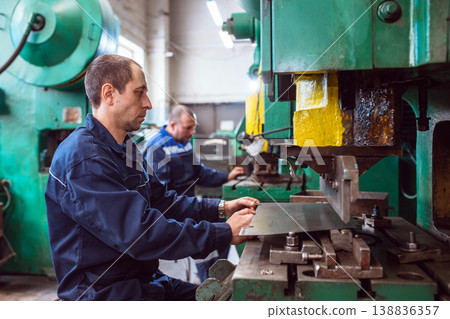 Metal Formation by Hydraulic Press. Factory Worker at Work. Worker operating metal press machine at workshop. 138836357