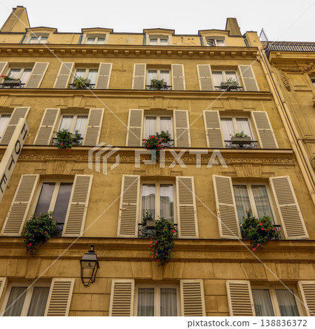 Parisian building facade showcasing traditional architecture, windows with open shutters, balconies, and vibrant flower boxes Parisian building facade showcasing traditional architecture, windows with open shutters, balconies, and vibrant flower boxes 138836372