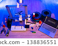 A 3D printer is actively creating the word HOME on its build plate, surrounded by spools of filament, tools, and a laptop displaying the same word 138836551