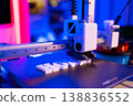 A close-up shot of a 3D printer in action, meticulously building white letters on its platform under vibrant blue and pink lighting 138836552