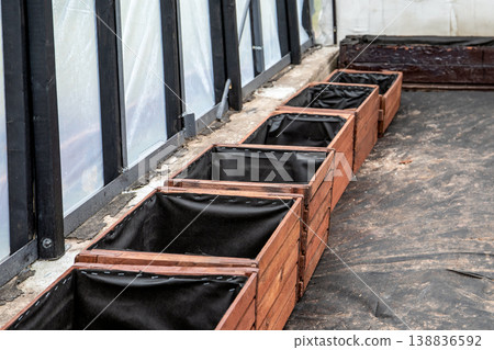 Arranging Wooden Planter Boxes in a Straight Row Inside Greenhouse Growing Space Arranging Wooden Planter Boxes in a Straight Row Inside Greenhouse Growing Space 138836592