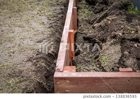 Aligning Wooden Raised Garden Bed Frame Inside Prepared Soil Trench Outdoors Aligning Wooden Raised Garden Bed Frame Inside Prepared Soil Trench Outdoors 138836593