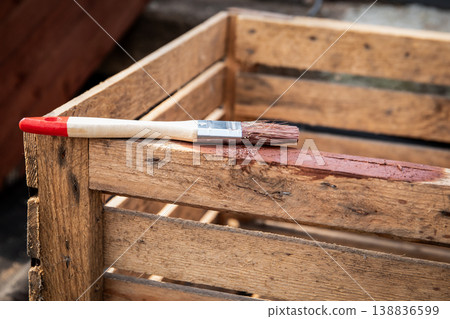Painting Wooden Crate With Brush Applying Protective Coating Outdoors Painting Wooden Crate With Brush Applying Protective Coating Outdoors 138836599