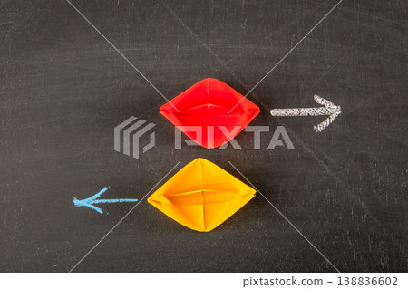 Opposite Direction Strategy Concept With Red and Yellow Paper Boats and Arrows Opposite Direction Strategy Concept With Red and Yellow Paper Boats and Arrows 138836602