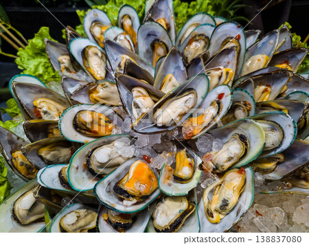 Fresh raw green-lipped mussels arranged on crushed ice at a luxury seafood market, high-quality shellfish platter with gourmet ingredients for culinary recipes and commercial restaurant advertising 138837080
