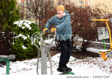 Senior woman exercising on outdoor fitness machine in winter 138837109