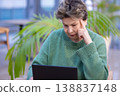 Mature woman working on laptop in shopping mall interior 138837148
