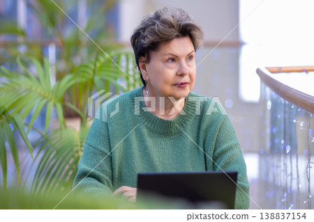 Mature woman working on laptop in shopping mall interior 138837154