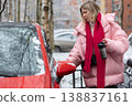 Young woman entering red car in winter city 138837161