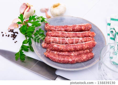 Plate of raw longaniza wit greens, garlic and spices prepared for cooking Plate of raw longaniza wit greens, garlic and spices prepared for cooking 138839130