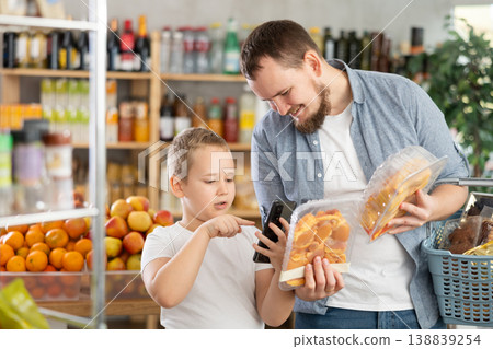 Man with preteen son scanning barcode on packaged chicken in grocery store Man with preteen son scanning barcode on packaged chicken in grocery store 138839254