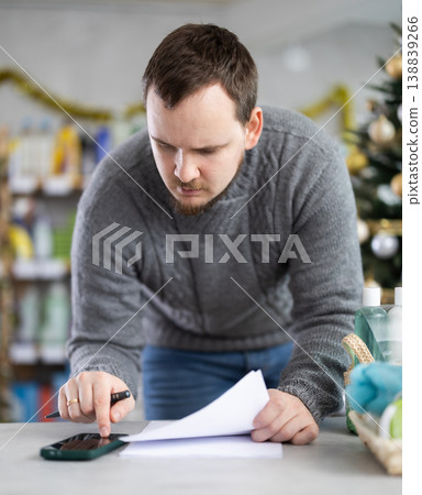 Male businessperson with paper document, plans to replenish restock stores inventory on Christmas Eve Male businessperson with paper document, plans to replenish restock stores inventory on Christmas Eve 138839266