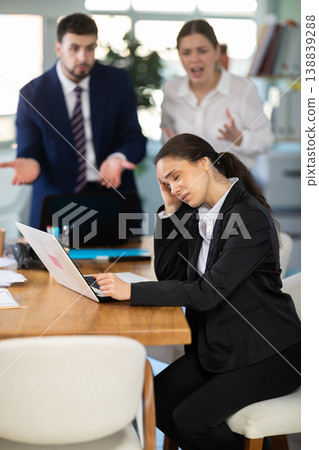 Group of people scolding sad colleague sitting at laptop in office Group of people scolding sad colleague sitting at laptop in office 138839288