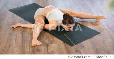 Flexible girl performing Kurmasana or Turtle Pose on mat Flexible girl performing Kurmasana or Turtle Pose on mat 138839392