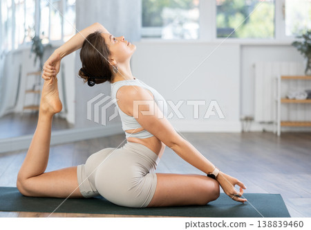 Athletic girl meditates in chandrasana pose in gym Athletic girl meditates in chandrasana pose in gym 138839460